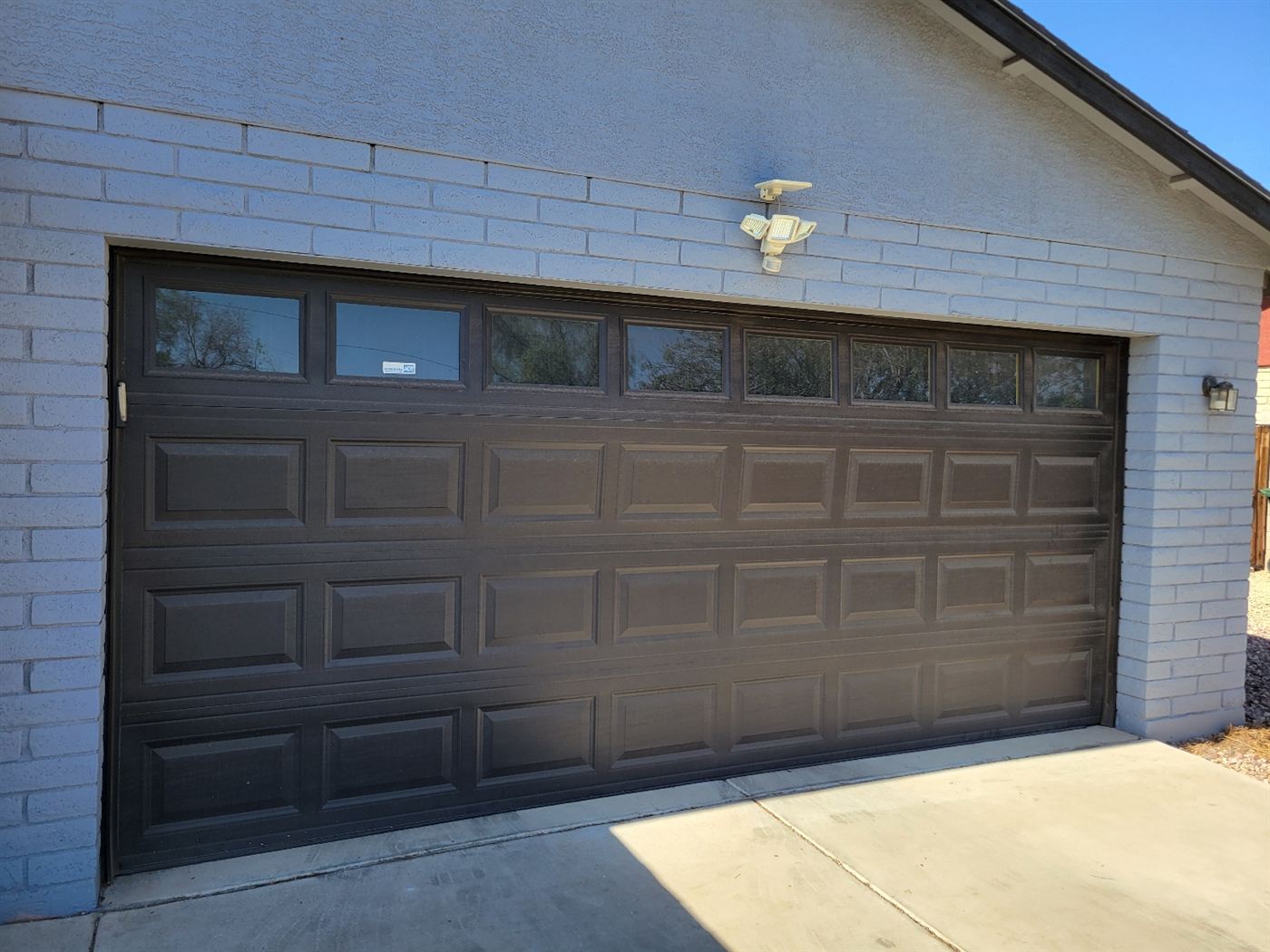 New dark brown raised-panel garage door with windows