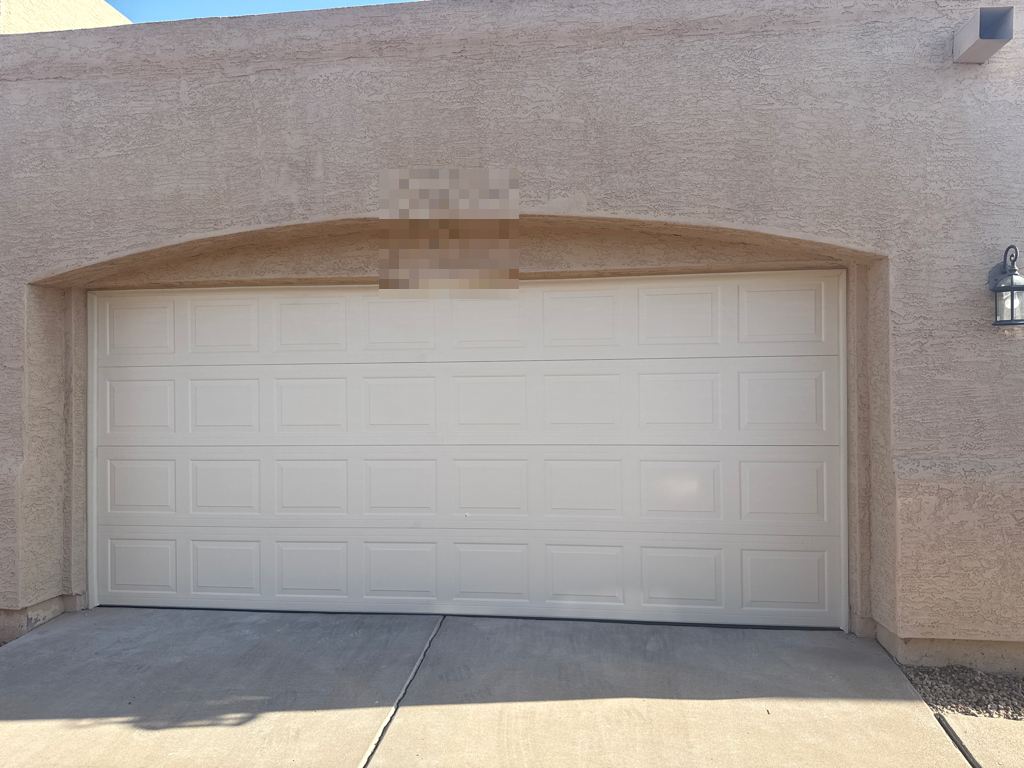 New raised-panel garage door under an arched stucco opening