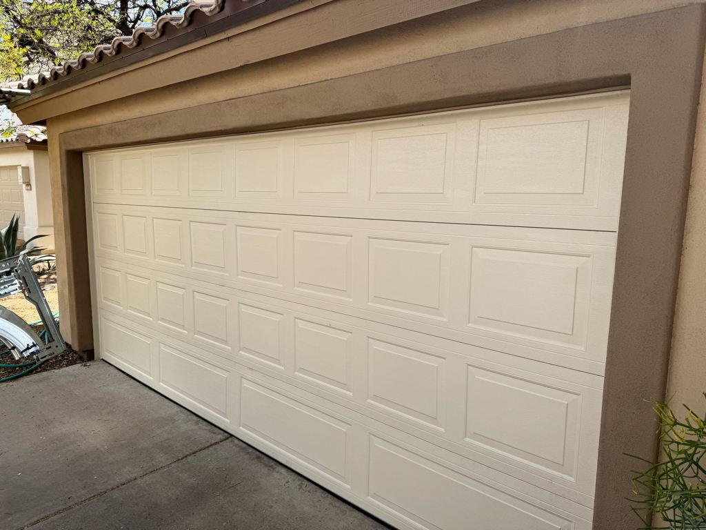 New raised-panel garage door on a stucco home